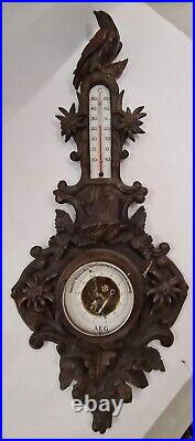 A richly carved large barometer with a thermometer IN BLACK FOREST STYLE
